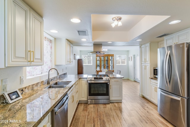 kitchen with light wood-type flooring, sink, kitchen peninsula, island exhaust hood, and stainless steel appliances