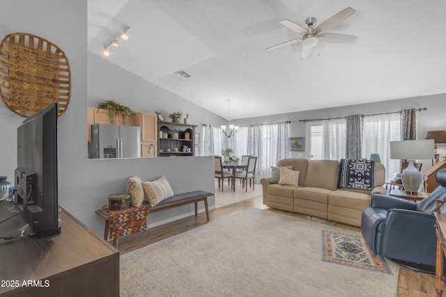 living room with lofted ceiling, plenty of natural light, ceiling fan with notable chandelier, and light hardwood / wood-style floors