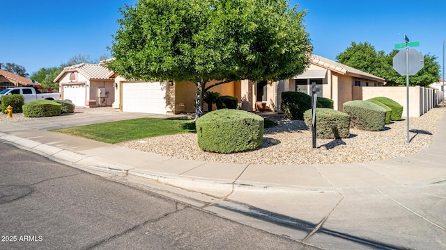 2615 N 123rd Dr, Avondale, AZ 85392 - view of property hidden behind natural elements featuring an attached garage, driveway, stucco siding, and a tiled roof