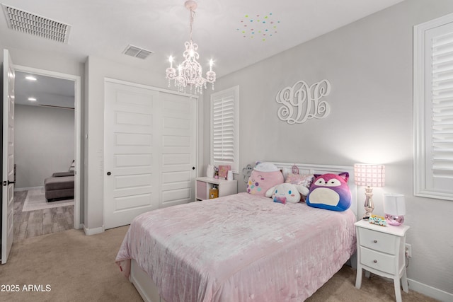 bedroom with light carpet, a closet, and a notable chandelier