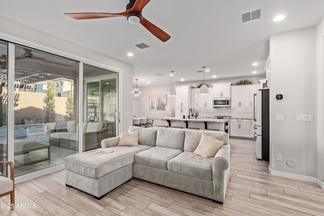 living room with sink, ceiling fan, and light hardwood / wood-style floors