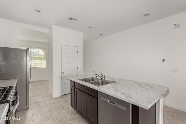 kitchen with stainless steel appliances, a kitchen island with sink, dark brown cabinetry, and sink