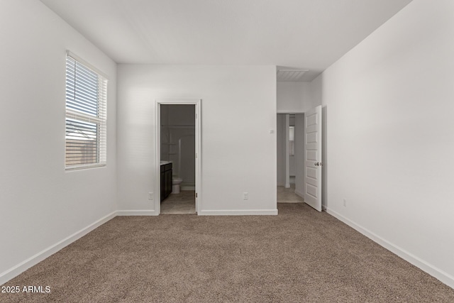 unfurnished bedroom featuring a walk in closet, ensuite bathroom, and carpet