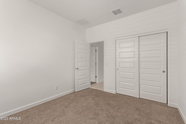 unfurnished bedroom with a closet and light colored carpet