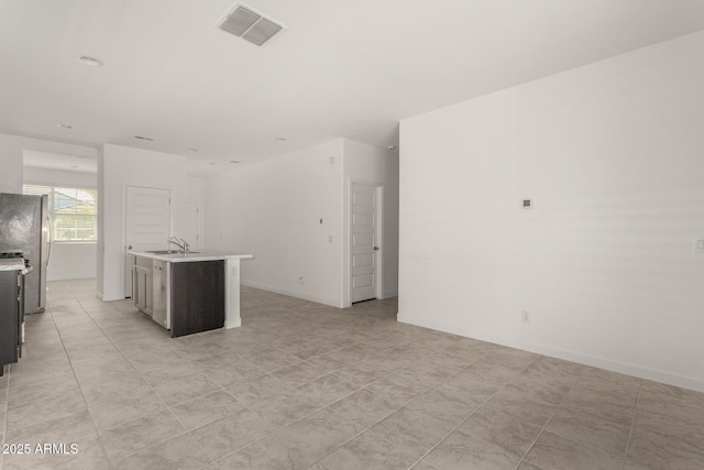 kitchen featuring stainless steel refrigerator, a kitchen island with sink, and sink