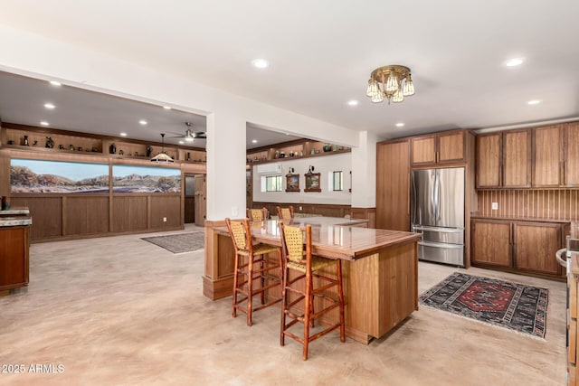 8752 E Range Rider Trl, Mesa, AZ 85207 - kitchen featuring freestanding refrigerator, brown cabinetry, recessed lighting, finished concrete flooring, and a breakfast bar
