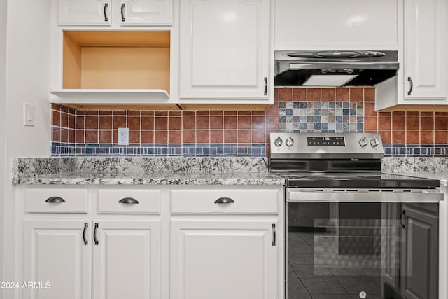 kitchen featuring decorative backsplash, light stone counters, ventilation hood, white cabinetry, and stainless steel electric range