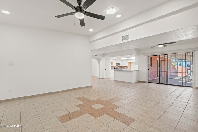 unfurnished living room with ceiling fan, light tile patterned floors, and a textured ceiling