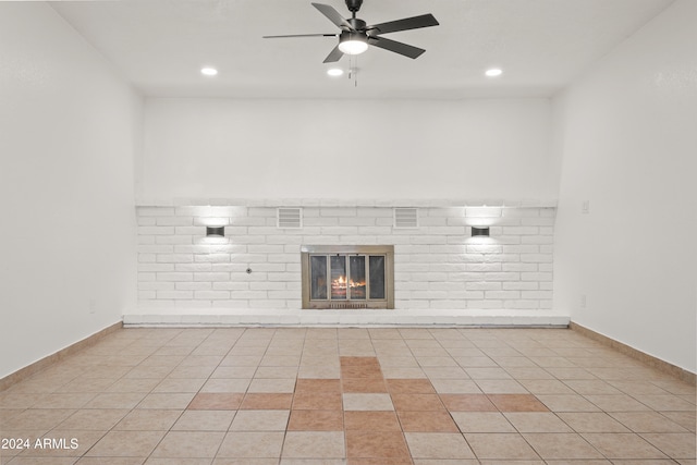 unfurnished living room with ceiling fan, light tile patterned floors, and a brick fireplace