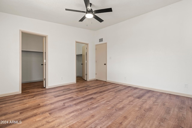 unfurnished bedroom featuring ceiling fan, light wood-type flooring, a spacious closet, and a closet