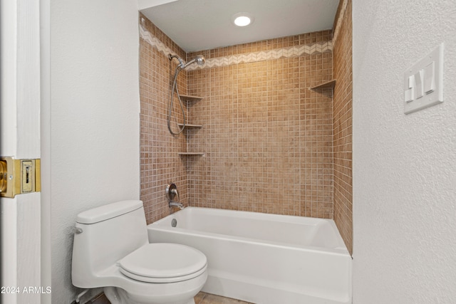 bathroom with tiled shower / bath combo and toilet