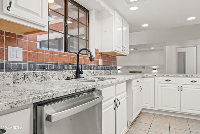 kitchen featuring dishwasher, sink, decorative backsplash, light tile patterned flooring, and white cabinetry