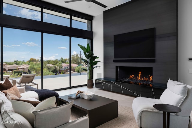 living area featuring a wall of windows, ceiling fan, and a fireplace