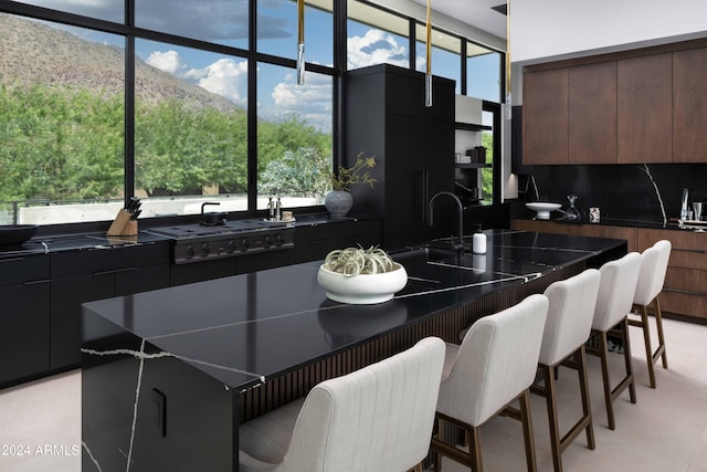 kitchen featuring modern cabinets, a breakfast bar, a sink, dark countertops, and backsplash