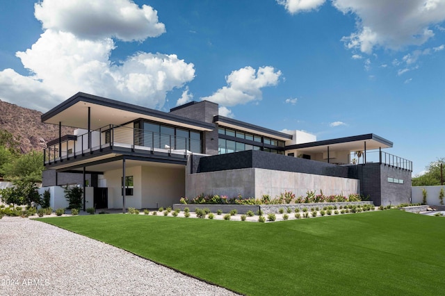back of property featuring stucco siding, a lawn, and a balcony