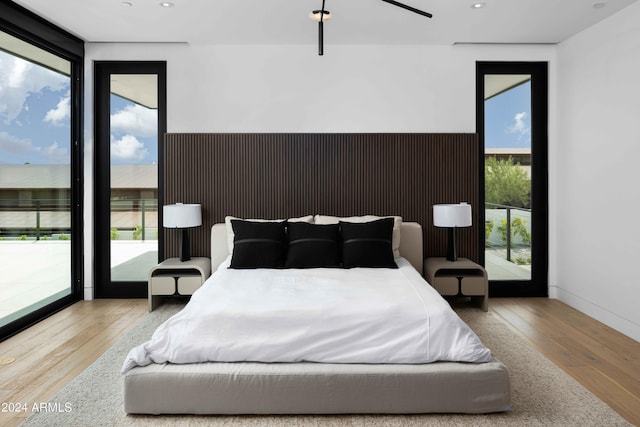 bedroom with recessed lighting, access to outside, baseboards, and wood finished floors