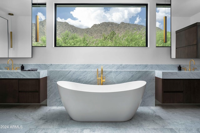 bathroom with two vanities, marble finish floor, and a healthy amount of sunlight