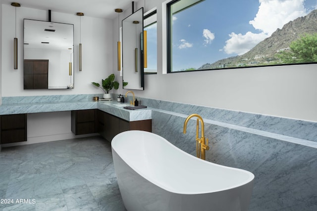 bathroom featuring marble finish floor, a freestanding bath, and vanity
