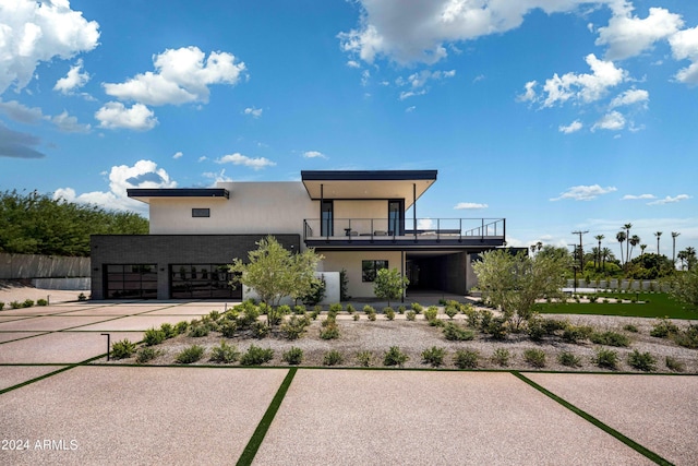 view of front of property with a garage, driveway, a balcony, and stucco siding