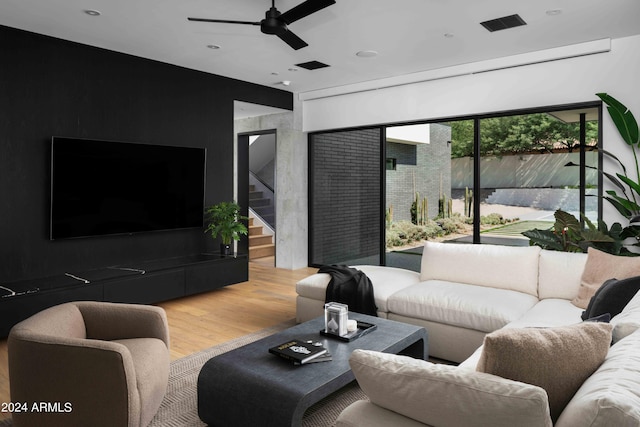 living room featuring stairs, wood finished floors, and ceiling fan