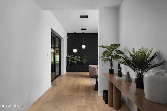 corridor with light wood-style flooring and baseboards