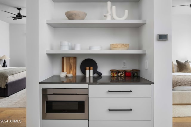 kitchen featuring a ceiling fan, white cabinetry, open shelves, wood finished floors, and dark countertops
