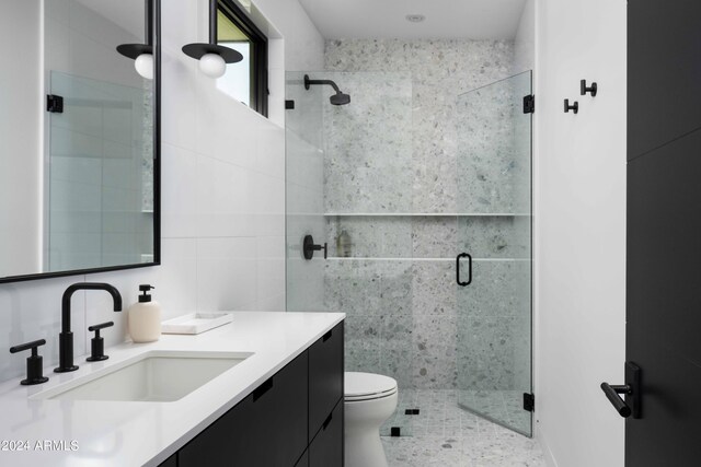 bathroom featuring toilet, vanity, tile walls, and a stall shower