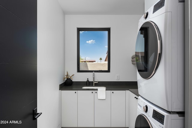 laundry room with stacked washer / dryer, a sink, and cabinet space