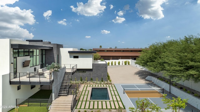 exterior space with a tennis court, stucco siding, fence, and stairway