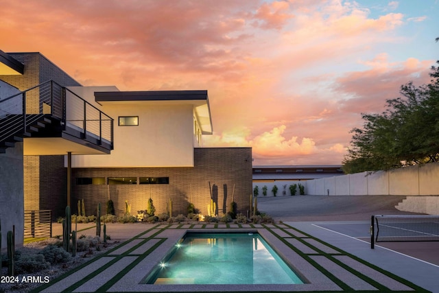 pool with a tennis court and fence