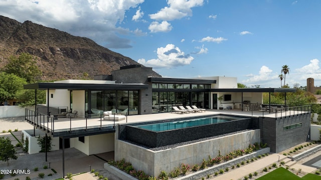 outdoor pool featuring a mountain view, a patio area, and a hot tub
