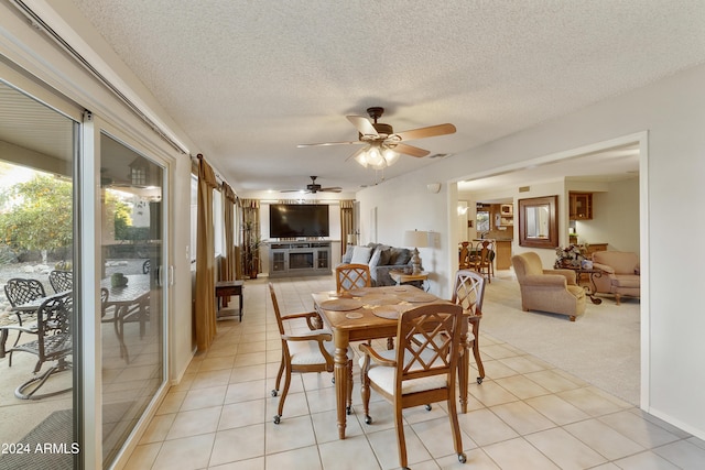 dining space with ceiling fan, light colored carpet, and a textured ceiling