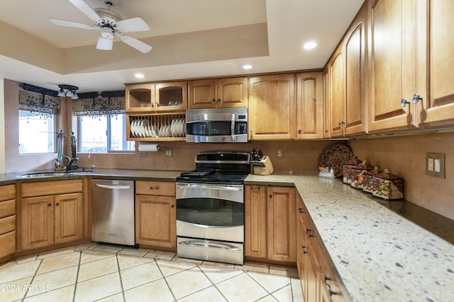 kitchen with light tile patterned flooring, appliances with stainless steel finishes, a raised ceiling, and sink