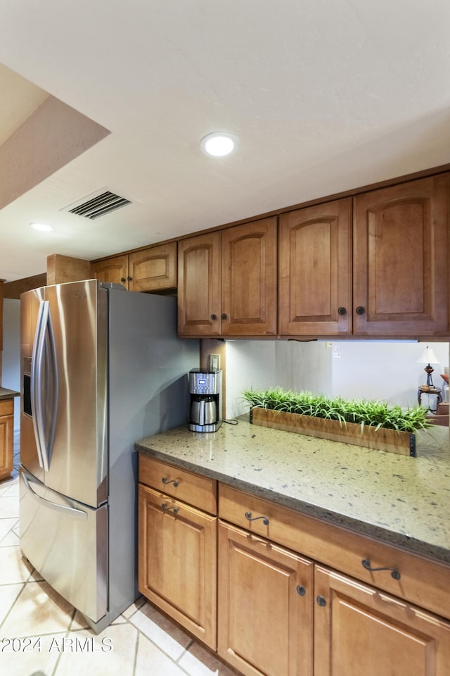 kitchen with light stone countertops, light tile patterned floors, and stainless steel refrigerator with ice dispenser