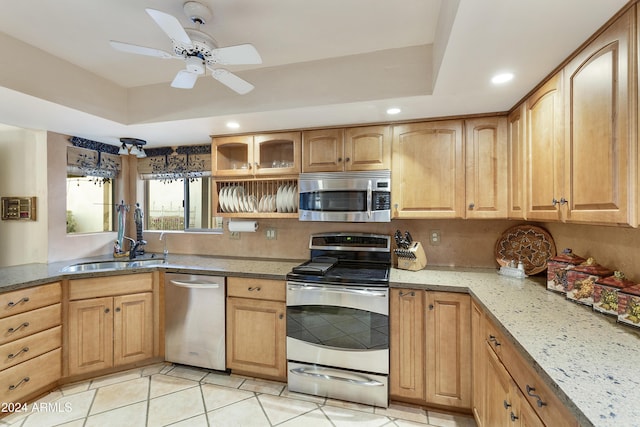 kitchen featuring light stone countertops, light tile patterned floors, stainless steel appliances, and a raised ceiling