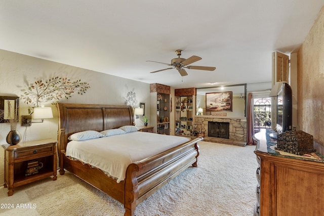 bedroom featuring ceiling fan, a fireplace, and light carpet