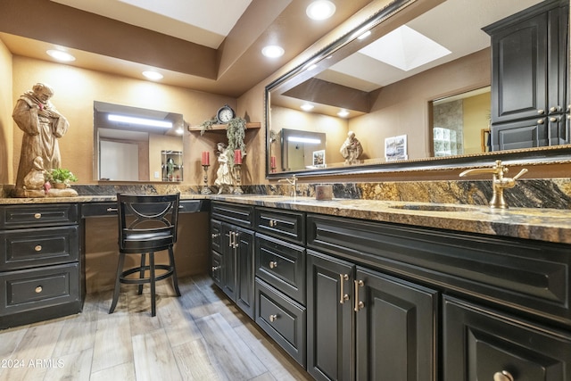 bathroom with hardwood / wood-style flooring, vanity, and a skylight