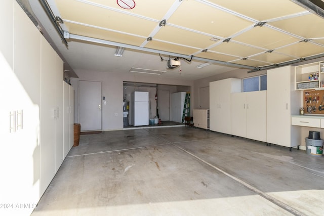 garage with a workshop area, white refrigerator, and a garage door opener