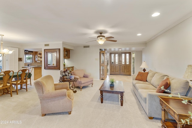 living room featuring light carpet, ceiling fan with notable chandelier, and ornamental molding