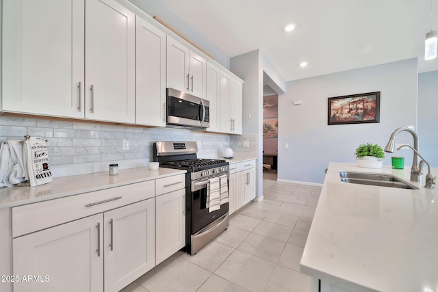 kitchen with stainless steel appliances, a sink, white cabinets, light countertops, and backsplash