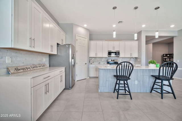 kitchen with white cabinets, stainless steel appliances, light countertops, and hanging light fixtures