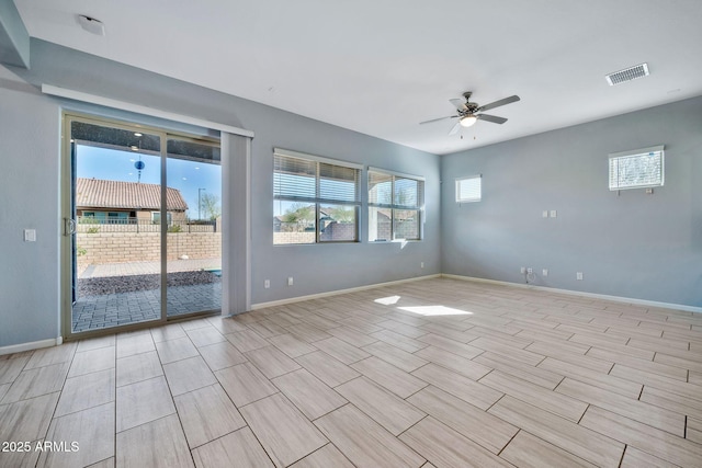 spare room featuring a ceiling fan, a wealth of natural light, and baseboards