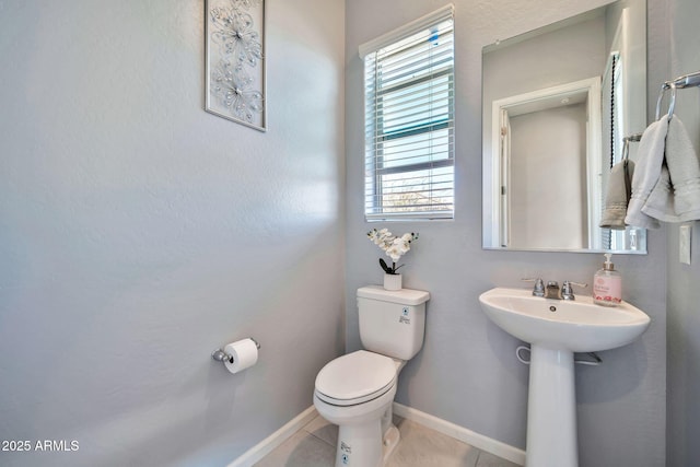 half bath featuring baseboards, toilet, and tile patterned floors