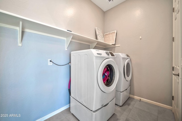 laundry area with laundry area, washer and clothes dryer, baseboards, and light tile patterned floors