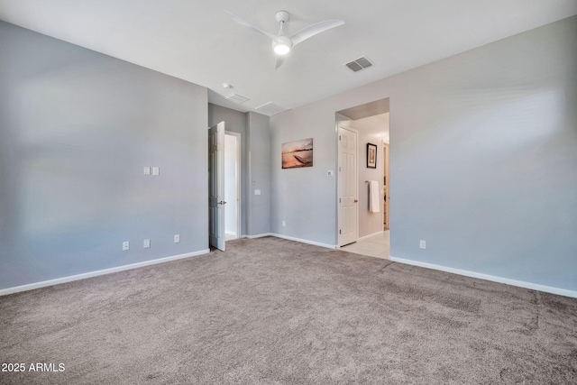 empty room featuring a ceiling fan, light colored carpet, visible vents, and baseboards