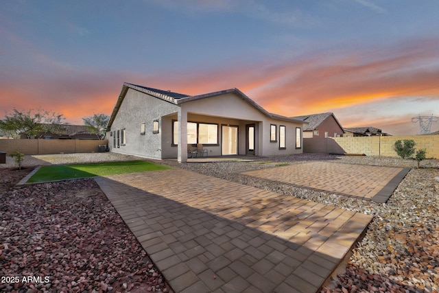 rear view of house featuring a patio area, a fenced backyard, and stucco siding