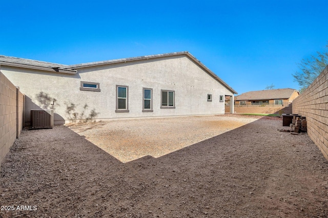 back of property featuring a fenced backyard, cooling unit, and stucco siding