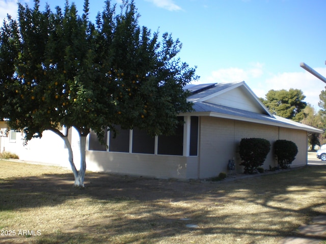 view of side of property featuring a lawn and solar panels