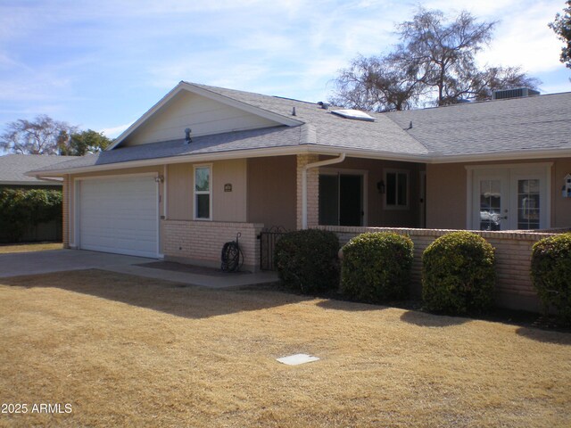 single story home with an attached garage, roof with shingles, concrete driveway, and brick siding