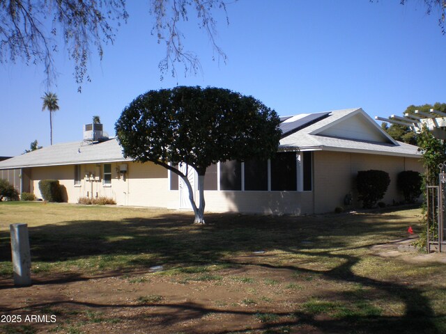 view of side of home featuring roof mounted solar panels and a lawn